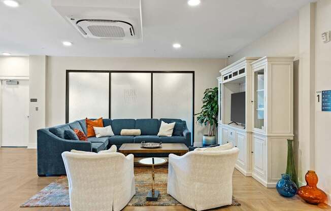 A living room with a blue couch and two white chairs.