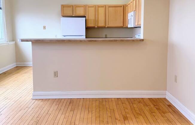 an empty living room with wood floors and a kitchen