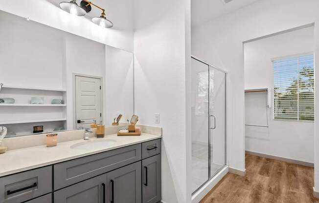 A bathroom with a white counter top and a walk in shower.
