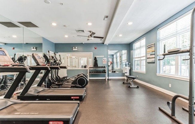 a gym with treadmills and other exercise equipment and windows