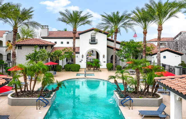 a large swimming pool in front of a house with palm trees