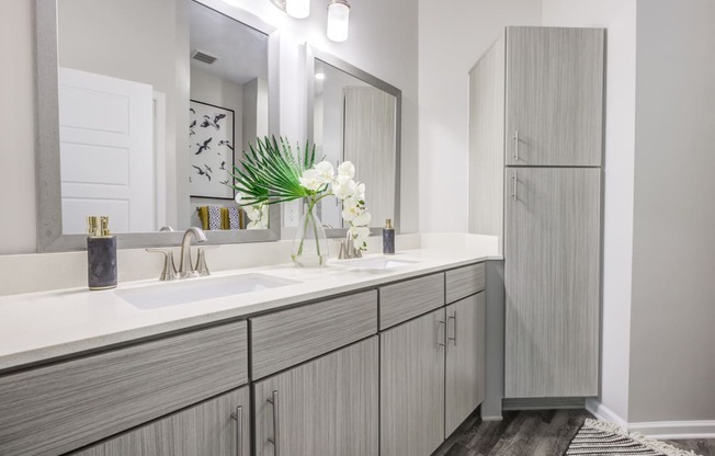 a bathroom with gray cabinets and white countertops at Century University City, Charlotte, North Carolina