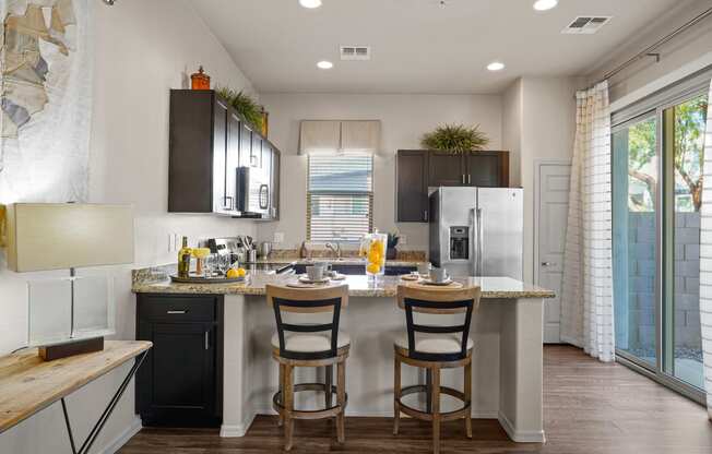 a kitchen with a island with two chairs and a refrigerator