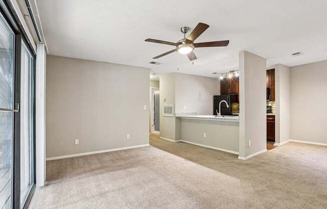 A spacious room with a ceiling fan and carpeted floor.