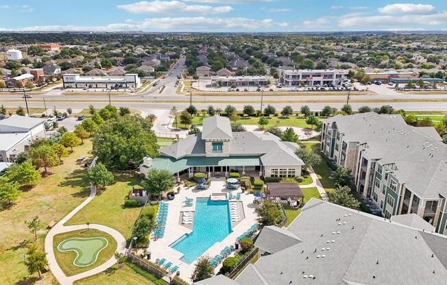 A large building with a pool in the foreground and a golf course behind it.