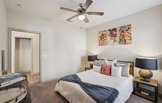 A bedroom with a bed, nightstands, and a ceiling fan.