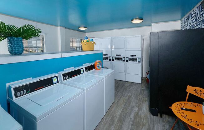Watermark Apartments on-site laundry facility in Lakeland, Fl with combined and separate washer and dryer units, vending machine, and seating area.