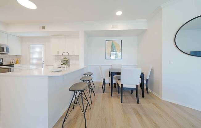 A kitchen with white cabinets and a white island with a bar stool.
