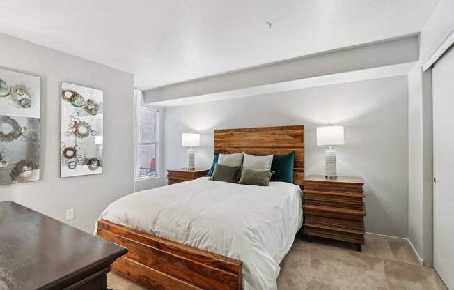 A bedroom with a bed, nightstand, and wall art.