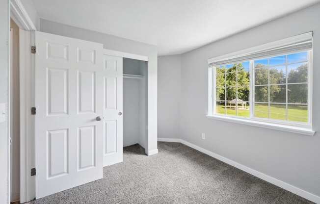 a living room with a large window and a carpet floor