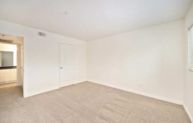 a spacious living room with carpet and a door to the bathroom