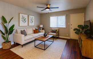 A living room with a beige couch, a coffee table, and a ceiling fan.
