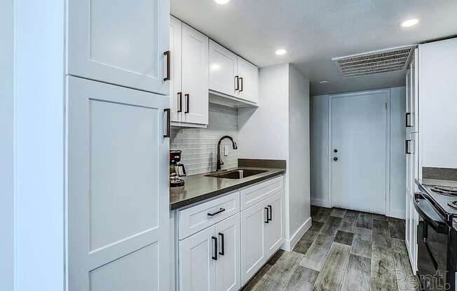 A kitchen with white cabinets and a wooden floor.