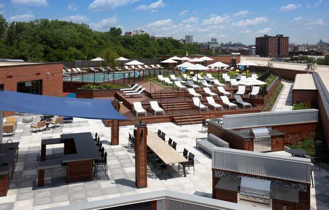an aerial view of the rooftop lounge area of a hotel with lounge chairs and tables at One Ten Apartments, Jersey City