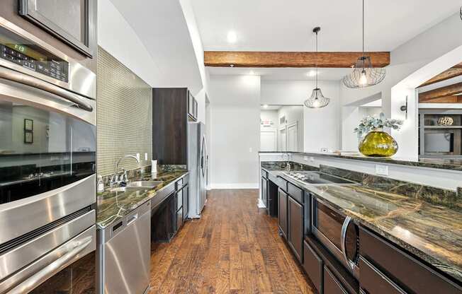 A modern kitchen with dark wood floors and stainless steel appliances.