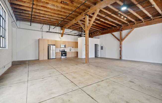 A large, empty room with wooden beams on the ceiling and tiled flooring.