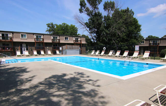 A large swimming pool surrounded by lounge chairs and trees.