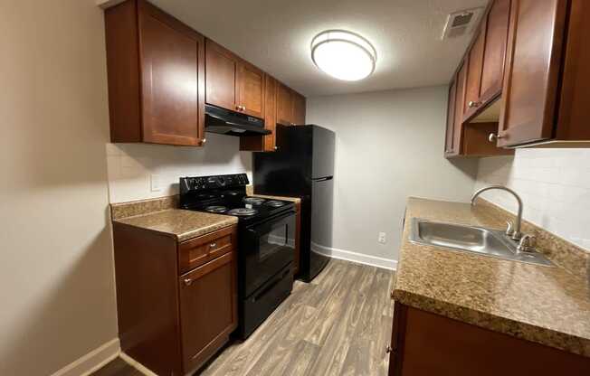 a kitchen with a black stove top oven next to a sink and a refrigerator