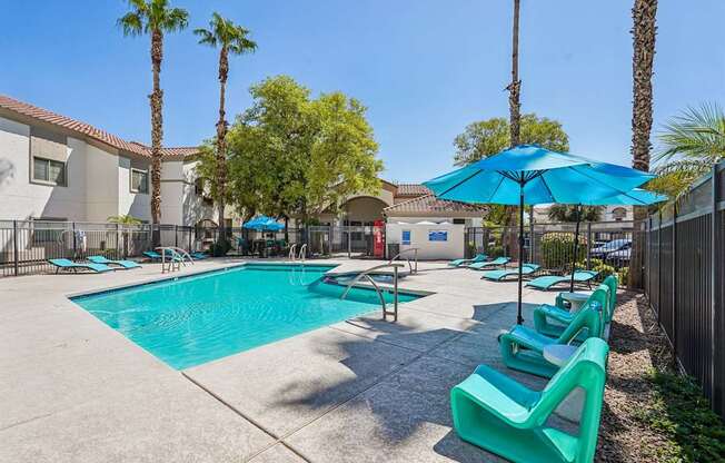 A pool surrounded by palm trees and sun loungers.