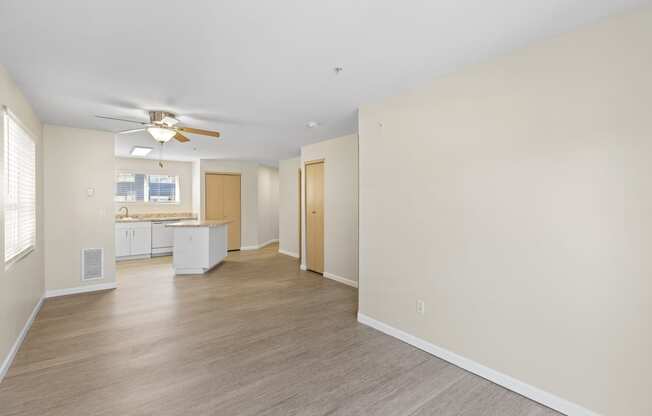 a spacious unfurnished living room with plank flooring and kitchen with an island in the background at Promenade at the Park Apartment Homes, Washington, 98125