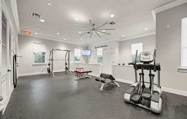 A gym with a variety of equipment including a treadmill, weights, and a bench.