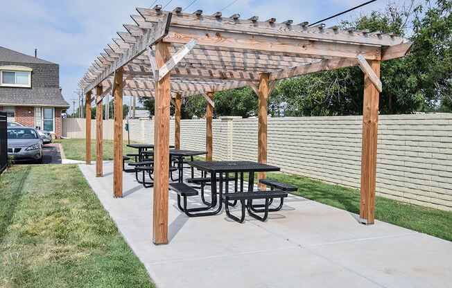 a picnic table under a wooden pergola in a backyard