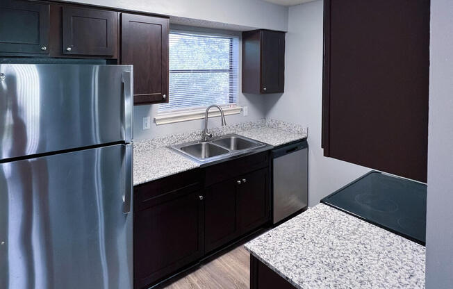 an empty kitchen with granite counter tops and stainless steel refrigerator