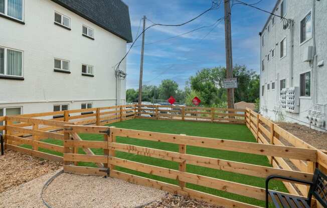 a green lawn in a wooden fence between two buildings