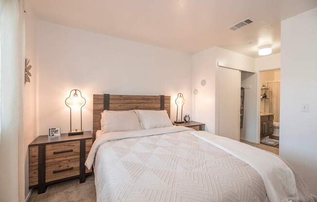 A bedroom with a large bed and two lamps on either side of the bed  at Sierra Glen Apartments, California, 95621