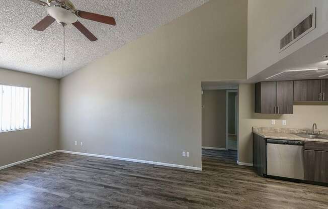 an empty living room and kitchen with a ceiling fan