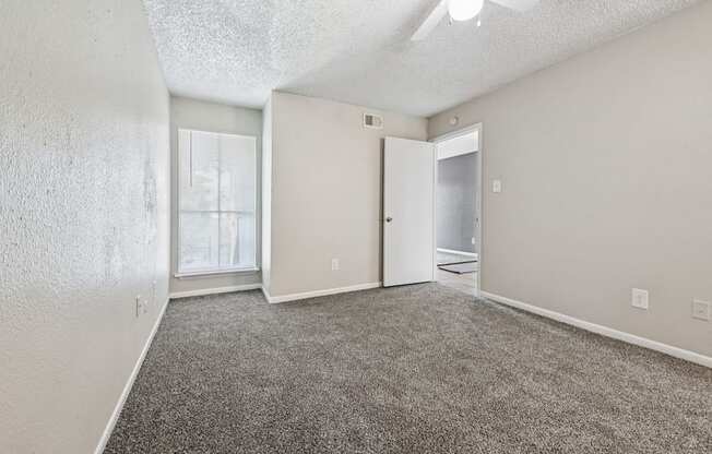A room with a carpeted floor and a ceiling fan.