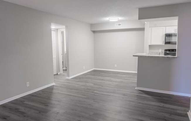 an empty living room and kitchen with wood flooring