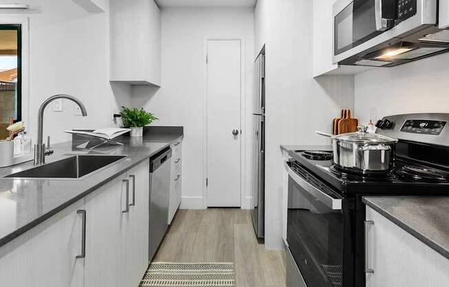 A modern kitchen with white cabinets and black countertops.