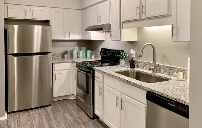 a kitchen with white cabinets, granite countertops, and stainless steel appliances