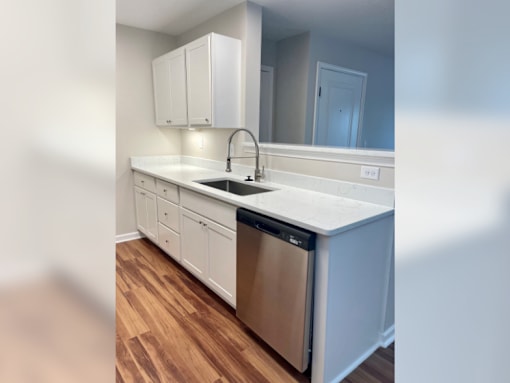 an empty kitchen with white cabinets and a stainless steel dishwasher