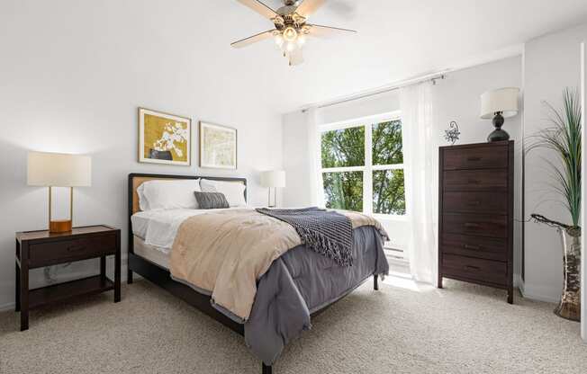 a bedroom with a large window and a ceiling fan