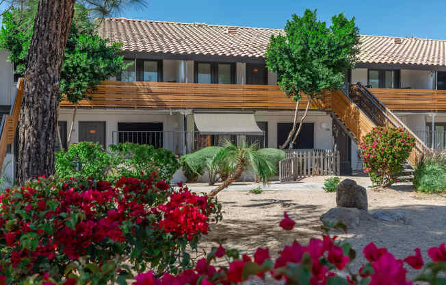 a view of a building with trees and flowers in front of it