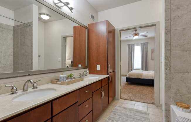 a bathroom with a sink and a mirror and a bedroom with a bed