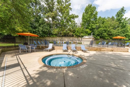 a hot tub with chaise lounge chairs and umbrellas