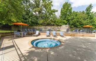 a hot tub with chaise lounge chairs and umbrellas