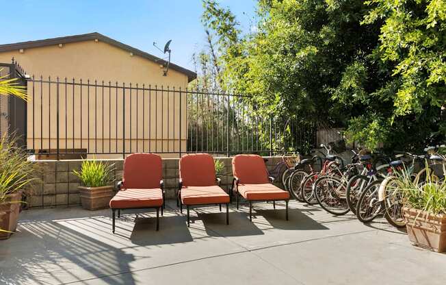 Apartments in Mar Vista CA - Vista - Outdoor Courtyard with Orange Cushioned Lounge Chairs, with Bike Rack, Trees, and Potted Plants