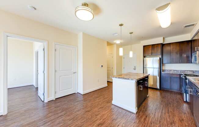 vacant living area with hardwood floors, view of kitchen with stainless steel appliances and kitchen island at archer park apartments in southeast Washington dc