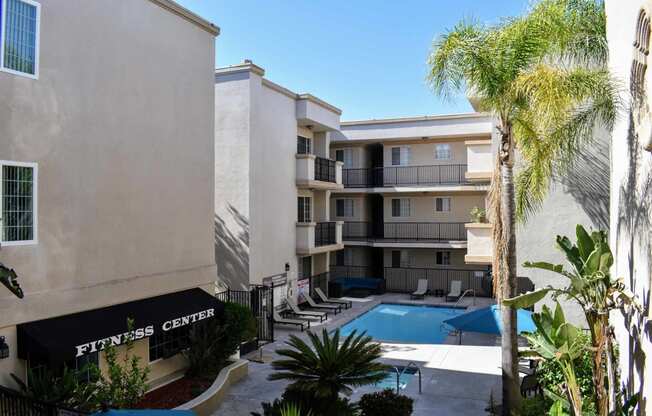 Elevated view from inside the property with entrance to fitness center, community pool, and tropical landscaping