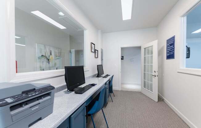 A white room with a desk and two computers on it.
