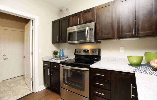 A kitchen with dark brown cabinets and stainless steel appliances.