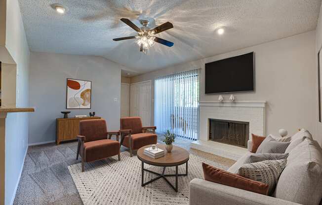 A living room with a fireplace, a television, and a ceiling fan.