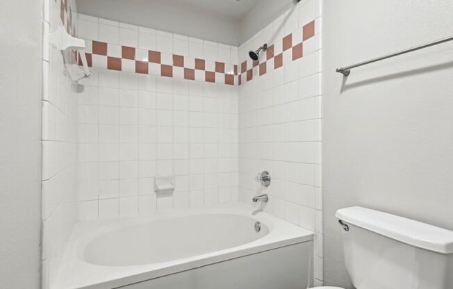 A white bathroom with a tub and toilet.