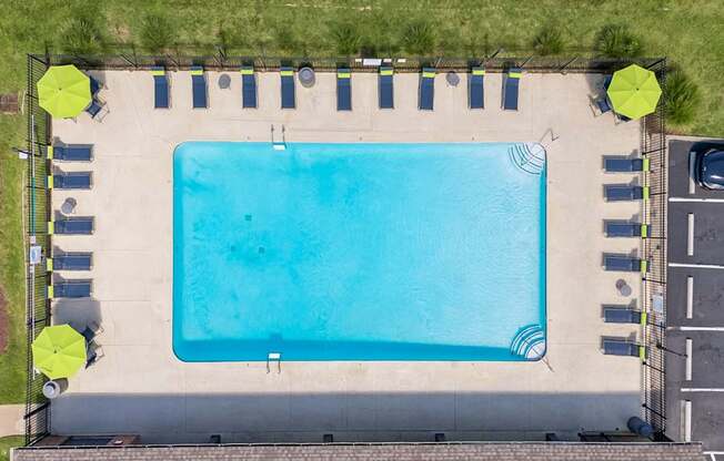 An aerial view of a swimming pool surrounded by lounge chairs and umbrellas.
