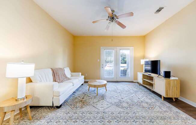 A living room with a white couch, a wooden coffee table, and a ceiling fan.