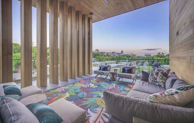 a living room with couches and chairs and a colorful rug with a view of the city